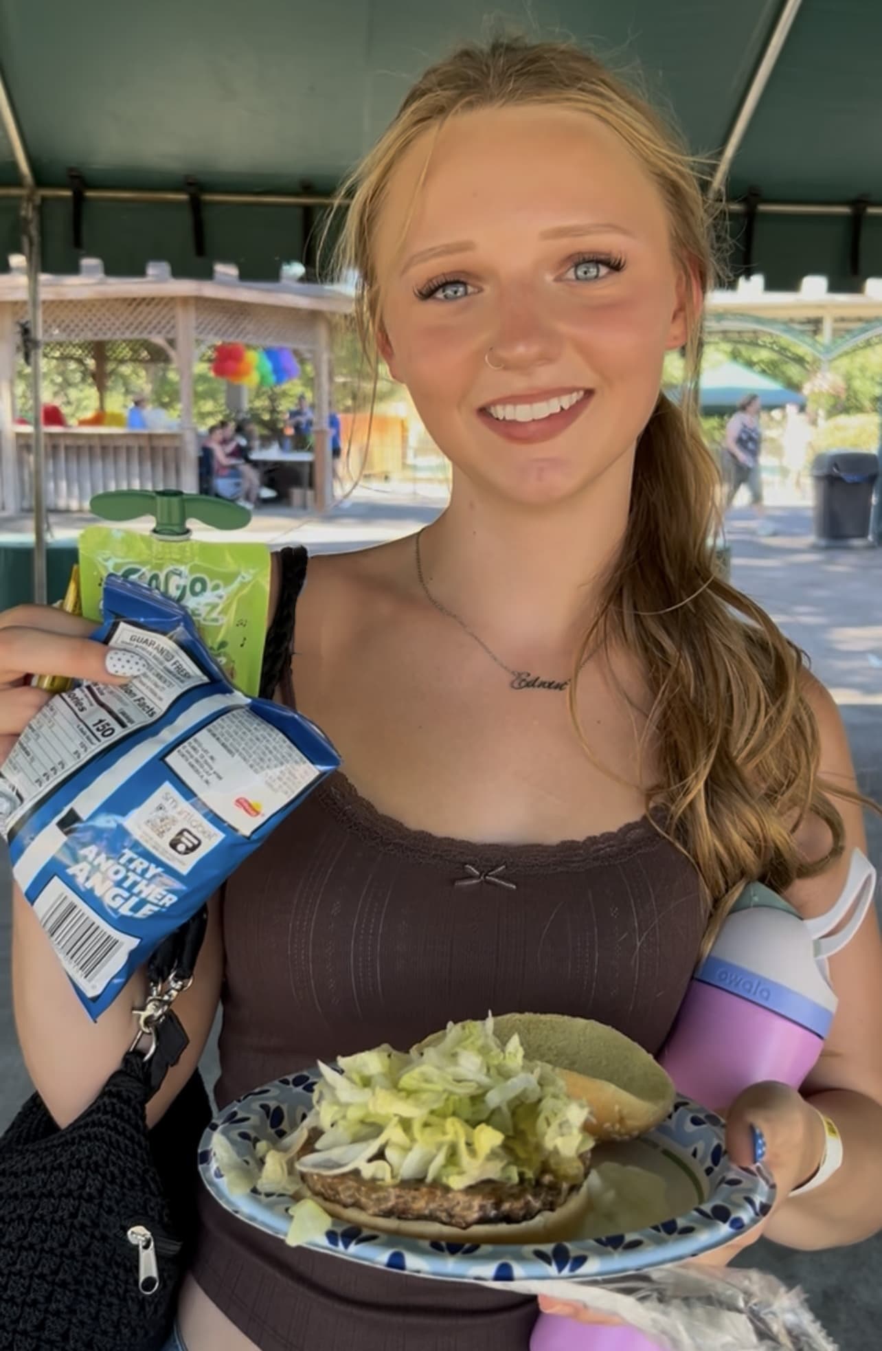 Guest smiling and holding a plate of food at an OGT outdoor event