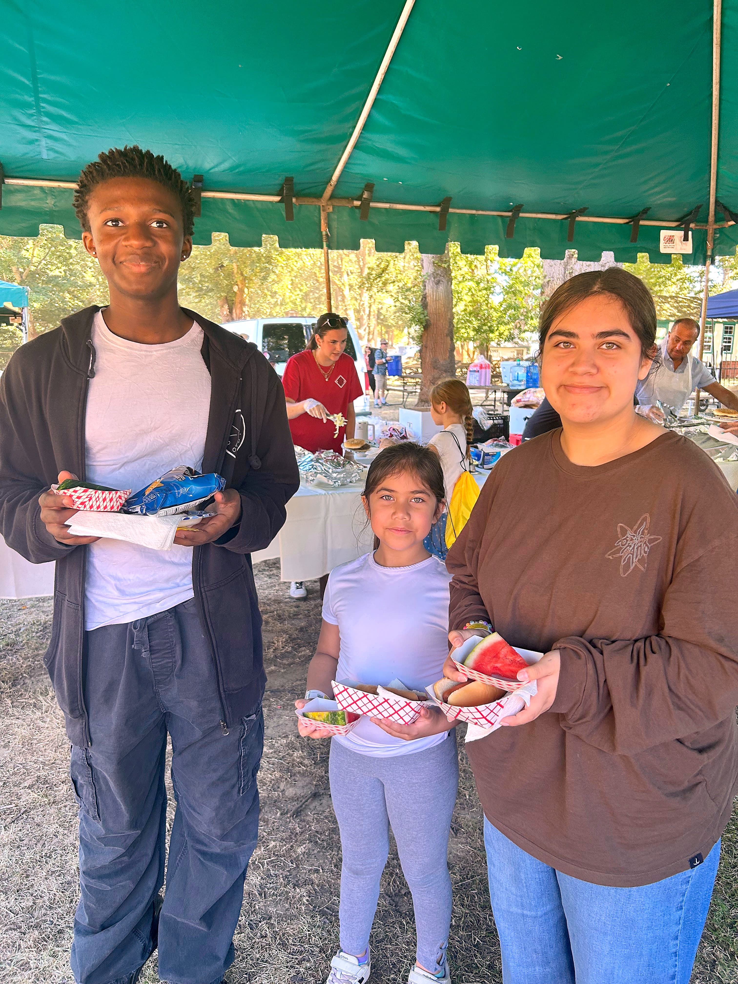 Teens enjoying snacks together under a tent at Oaks Park Day