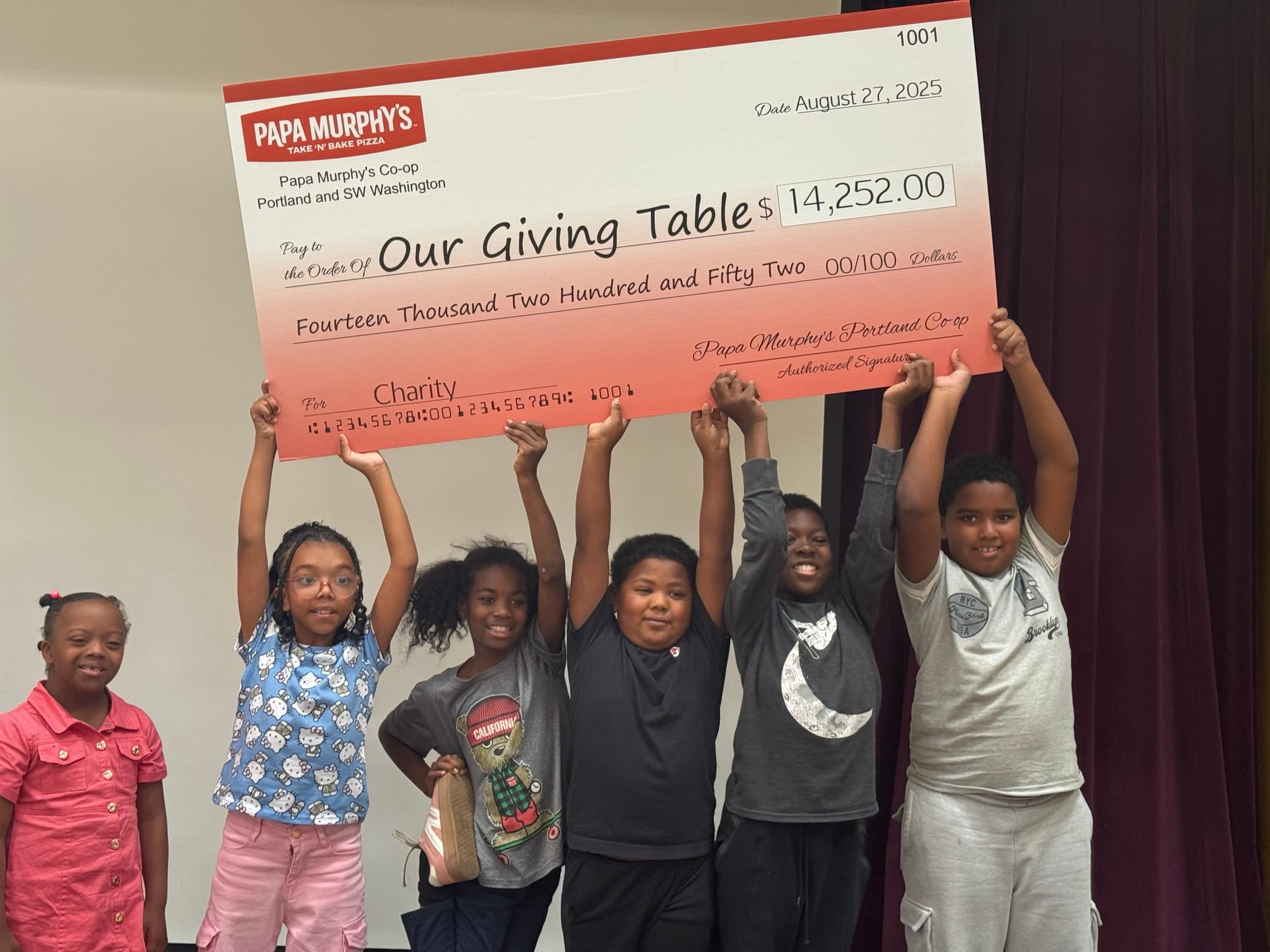 Kids holding up a $14,252 charity check from Papa Murphy's