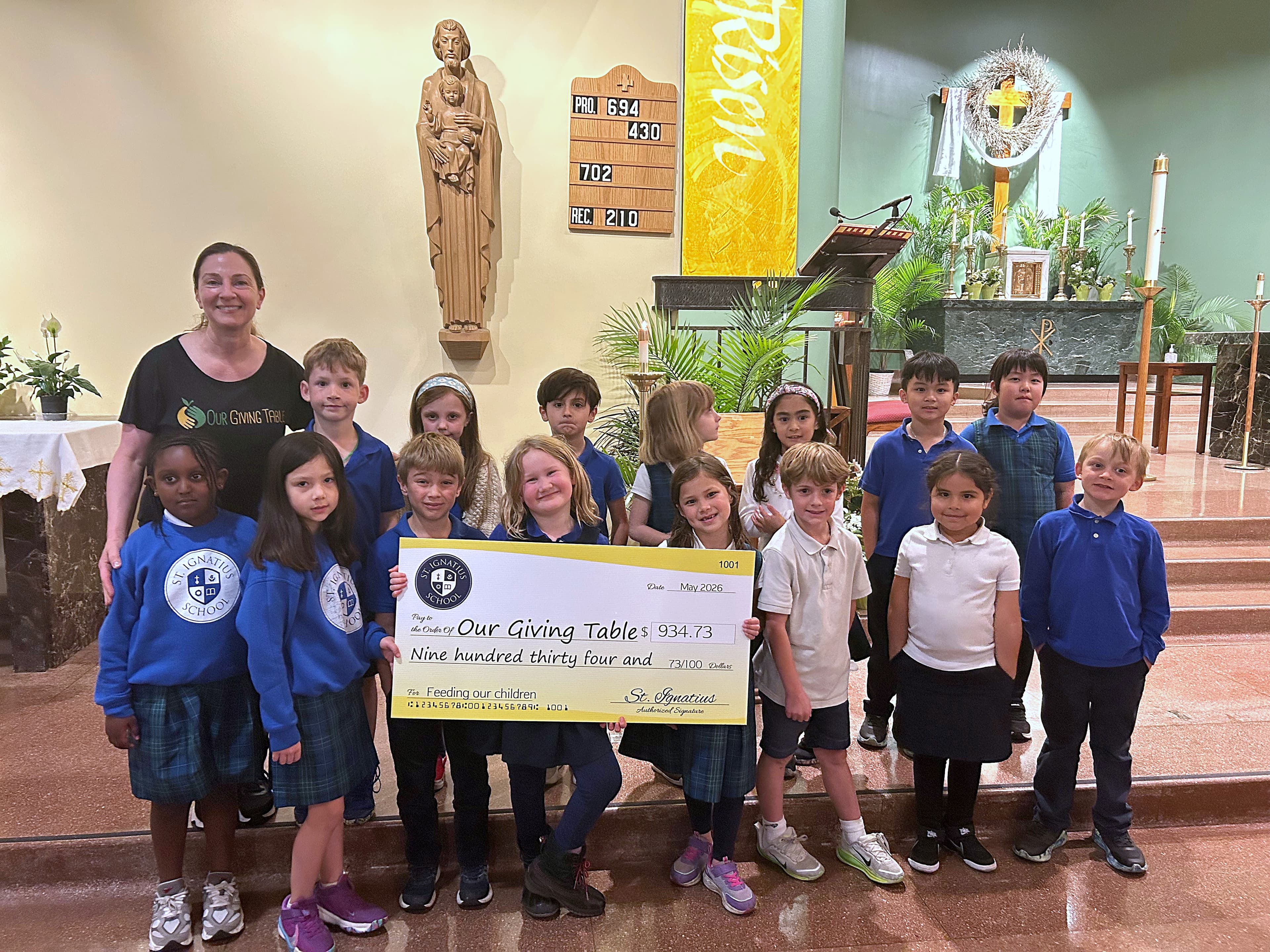 St. Ignatius School students presenting a $934.73 charity check to Our Giving Table
